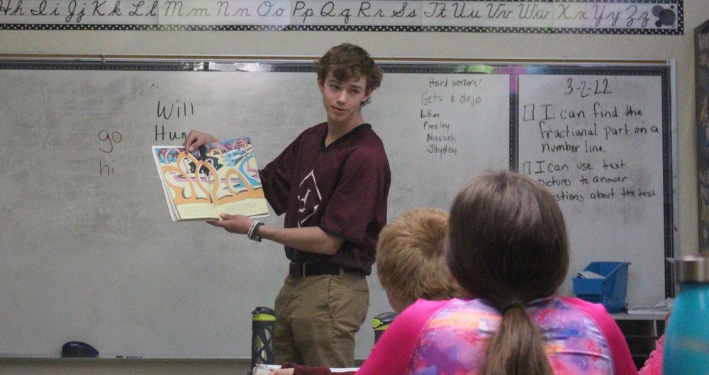 Baseball player reading to students